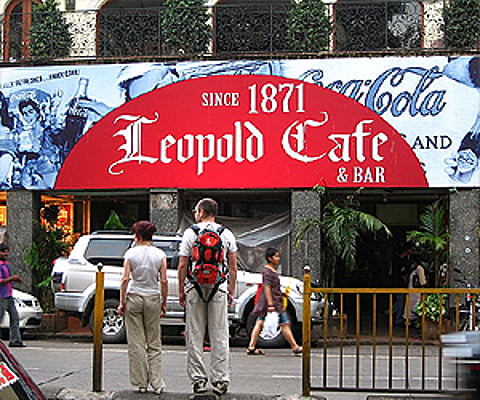 A couple of tourists in front of the Leopold Cafe in Mumbai. (Image reproduced as per the Wikimedia Commons license)
