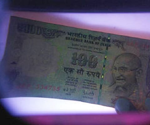 A man uses an electronic machine to check a currency note at a money exchange shop in Siliguri in this May 18, 2009 (File photo/Reuters)