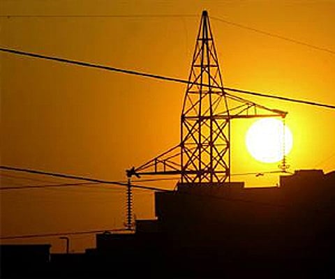 Sun sets behind a power tower near a building in New Delhi. (Photo: Reuters)