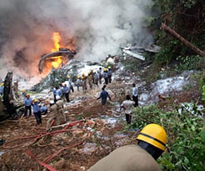 Firefighters perform rescue operations as people crowd around the wreckage of an Air India plane that crashed in Mangalore on Saturday. (AP)