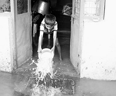 A boy bails out water from his flooded home in Indiramma Colony in Kavali in Nellore district on Sunday.
