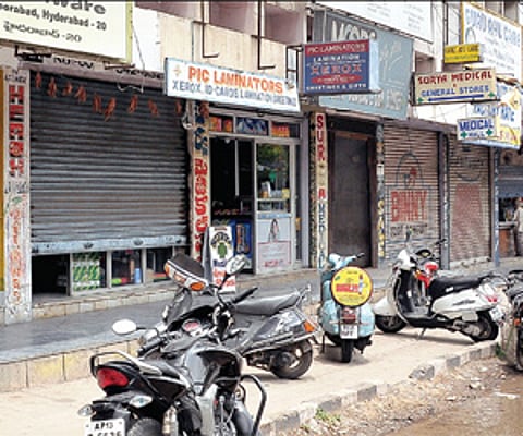 (Top) Shops at Musheerabad functioning with half-closed shutters during the Telangana bandh on Friday and (below) RTC bus drivers sleeping atop a bus