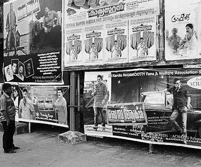 A man looking at posters from various Mammootty fan associations, wishing a Mammootty film the best of luck at the box office.