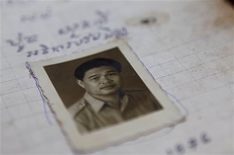 In this photo taken, July 18, 2014, an ID photo of Poch Younly is placed on his dairy displayed at the Documentation Center of Cambodia in Phnom Penh, Cambodia. Nearly 40 years ago, hunched on the floor of the wood and leaf hut he was forced to live in aw