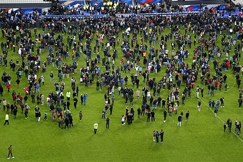Spectators invade the pitch of the Stade de France stadium after the international friendly soccer France against Germany, Friday, Nov. 13, 2015 in Saint Denis, outside Paris. At least 35 people were killed in shootings and explosions around Paris, many o