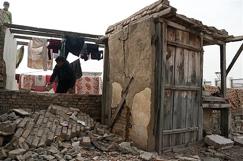 A man tries to repair a wall partially collapsed due to an earthquake in Peshawar, Pakistan, Saturday, Dec. 26, 2015. A strong earthquake shook parts of Pakistan and Afghanistan early Saturday, rattling buildings and forcing sleeping residents out of thei