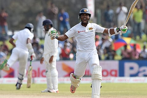 Sri Lankan cricketer Dinesh Chandimal (R) raises his bat after reaching a century (100 Runs) during the third day of the opening Test match between Sri Lanka and India at the Galle International Cricket Stadium in Galle. |AFP