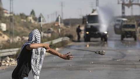 A Palestinian uses a sling shot to throw stones towards Israeli soldiers during clashes in Jalazoun Refugee Camp, near the West Bank city of Ramallah.