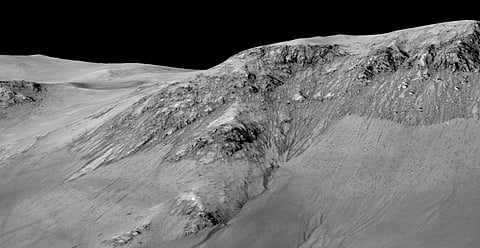 A handout image made available by NASA on September 27, 2015, shows dark, narrow, 100 meter-long streaks called recurring slope lineae flowing downhill on Mars, inferred to have been formed by contemporary flowing water | AFP