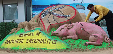 Artist Subal Maharana creates a sand sculpture on JE disease in Bhubaneswar on Saturday. | EPS