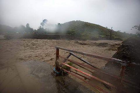 People watch from the other side of the La Digue river as water roars past the destroyed Petit Goave bridge, as Hurricane Matthew passes over, in Petit Goave, Haiti, Oct. 4, 2016. | AP