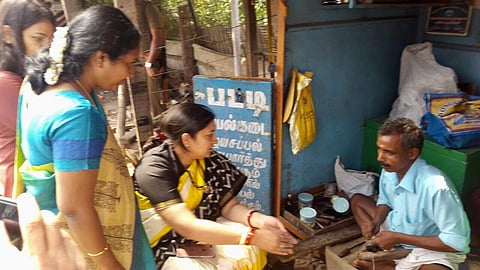 Union Minister Smriti Irani mends her sandal at a cobbler shop near Coimbatore during her visit to city on Saturday. | EPS