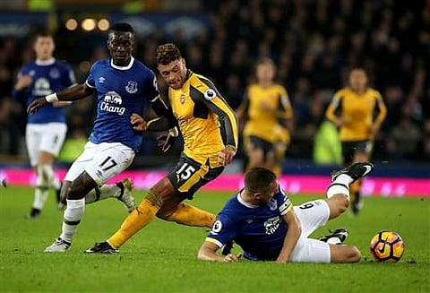 Arsenal's Alex Oxlade-Chamberlain, centre, contends with Everton players Idrissa Gueye, left, and Phil Jagielka, right, during their EPL match. (AP)