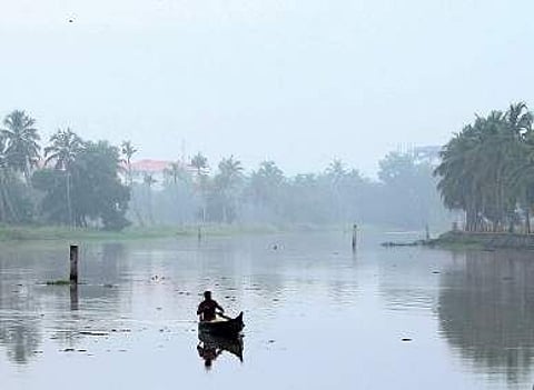 A lone fisherman rows down the Kadambrayar on a misty morning Express