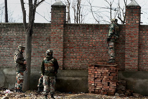 Security forces personnel take position outside the JKEDI building where militants have reportedly taken refuge after launching an attack on a CRPF convoy at Sampora Pampore near Srinagar on Sunday. | PTI