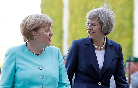 German Chancellor Angela Merkel, left, and British Prime Minister Theresa May walk on the red carpet during a military welcoming ceremony at the chancellery in Berlin. (AP)