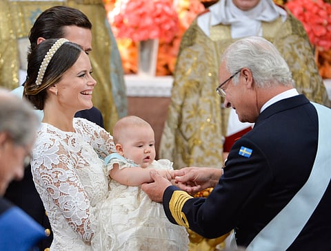 Sweden's Princess Sofia, left, holds up her five month-old son Prince Alexander, for King Carl Gustaf. right, during his christening at Palace Chapel in Drottningholm Palace | AP