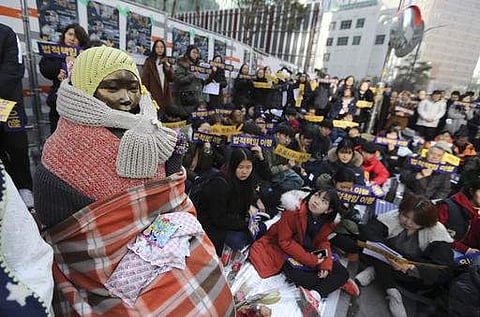 In this Wednesday, Jan. 4, 2017 photo, students gather near a statue of the girl representing thousands of Korean women enslaved for sex by Japan's imperial forces before and during World War II, during a weekly rally in front of the Japanese Embassy in S