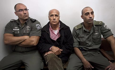 Israeli nuclear whistleblower Mordechai Vanunu sits between two prison guards as he waits in a courtroom before a hearing in Jerusalem. (File photo | AP)