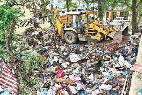 Corporation officials clear the waste from a single woman’s front yard in Jai Nagar, Koyambedu, using five mini tipper lorries and a front-loader. The woman is said to have collected the waste over a period of 12 years, in Chennai. | P Jawahar