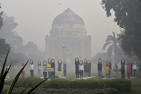 People performing yoga at Lodhi Garden as smog covers it in New Delhi on Friday morning, a day after Diwali. (PTI)