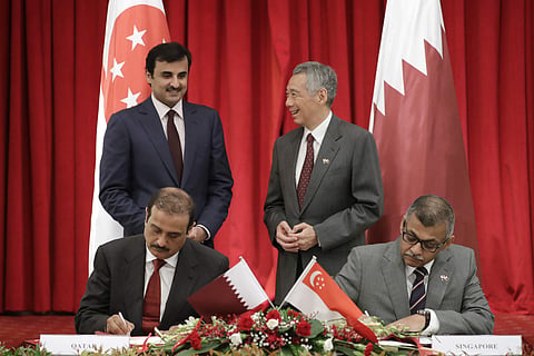 Qatar's Emir Sheikh Tamim bin Hamad Al Thani, back left, speaks with Singapore's Prime Minister Lee Hsien Loong, back right, as they witness the signing of the Memorandum of Guidance as to Enforcement of Money Judgements between the Supreme Court of Singa