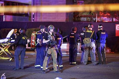Police officers and medical personnel stand at the scene of a shooting near the Mandalay Bay resort and casino on the Las Vegas Strip, Monday, Oct. 2, 2017, in Las Vegas.