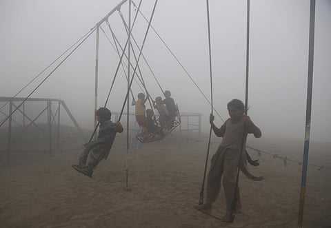 Children ride swings in a playground surrounded by smog in Lahore, Pakistan, Saturday, Nov. 11, 2017. (Associated Press)
