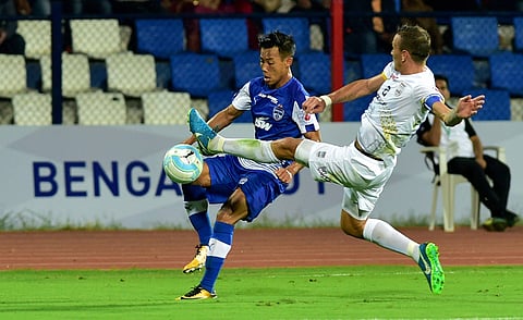 Bengaluru FC footballer Udanta Singh (blue jersey) and Mumbai FC player Gerson Fraga Vieira (White Jersey) vie for the ball during Indian Super League football match at Kanteerava Stadium in Bengaluru on Sunday. | PTI