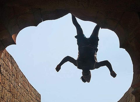 topsy-turvy: Jyothi Raj is seen dangling from a building at Chitradurga Fort using his feet. Performing a stunt like this requires not just strong leg muscles and a sturdy pair of shoes, but also a sense of balance