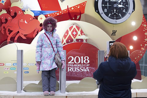 A girl poses for a photo in front of a clock counting down to the first match of the 2018 World Cup, which is installed on Manezh Square, outside the Kremlin in Moscow, Russia, Thursday, Nov. 30, 2017. | AP