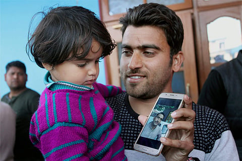 The daughter of rifleman Ravi Kumar, who was killed in an encounter with militants in Bandipora district of Kashmir on Tuesday, looks at his picture on a mobile phone, in Samba district on Wednesday | PTI