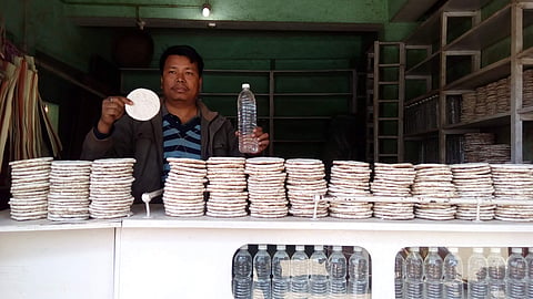 A local is seen holding a bottle of sekmai along with a piece of hamei