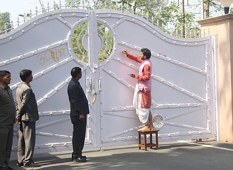 A priest paints 'swastika' and 'OM' signs outside the official bungalow of UP Chief Minister Yogi Adityanath in Lucknow. (PTI)