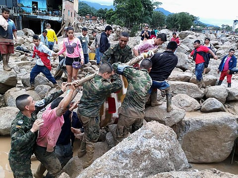 In this handout photo released by the Colombian National Army, soldiers and residents work together in rescue efforts in Mocoa, Colombia, Saturday, April 1, 2017, after an avalanche of water from an overflowing river swept through the city as people slept