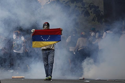 An anti-government protester holds a Venezuelan flag during clashes against security forces in Caracas, Venezuela, Wednesday, April 19, 2017. | AP