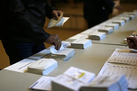 A man picks a ballot paper before voting for the first-round presidential election at a polling station in Paris, Sunday, April 23, 2017. | AP