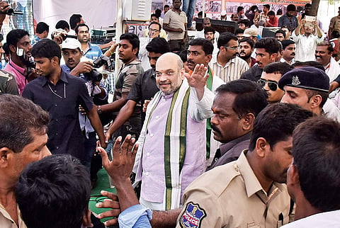 BJP president Amit Shah waves to the locals, (right) interacting with students at Gundrampally village in Nalgonda district on Wednesday | Vinay Madapu
