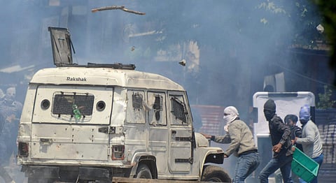 Youth attacks a police vehicle amid tear smoke fired by police during violent clashes | PTI