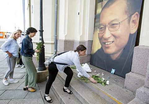 People place flowers and light candles in front of a picture of Liu Xiaobo, placed outside the Nobel's Peace center in Oslo, Thursday, July 13, 2017. (Audun Braastad/NTB scanpix via AP)