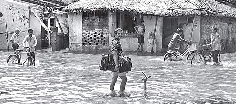 Residents of Sutahat, Dagbar Sahi, wade through an inundated street in Cuttack on Monday | EXPRESS