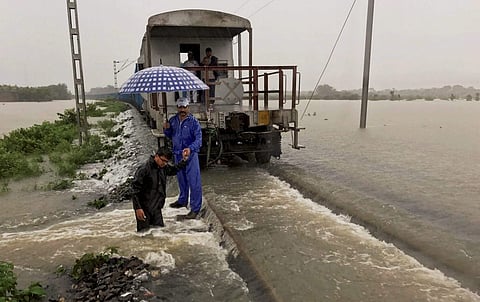 A goods train halts on the flooded tracks as railway empolyees inspect the damaged embankment along the Katihar-Guwahati line in Katihar district of Bihar on Monday. (PTI)