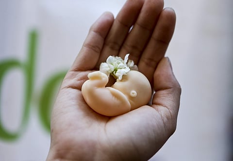 A woman holds a fetus doll in the palm of her hand. Used for representational purpose only.