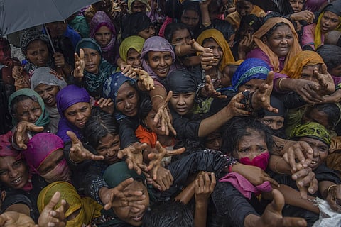 Rohingya Muslim women, who crossed over from Myanmar into Bangladesh, stretch their arms out to collect sanitary products distributed by aid agencies near Balukhali refugee camp, Bangladesh, Sunday, Sept. 17, 2017 | AP