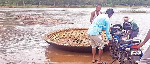 People loading a two-wheeler into a coracle at the border village of Anambadi in Gopinatham Range of Cauvery wildlife Sanctuary