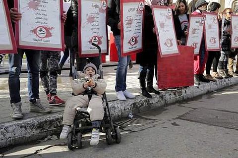 Family members of Tunisian who died in the revolution seven years ago, stage a protest while child in a baby-stroller rests in front of them in Tunis, Tunisia, Saturday, Jan. 13, 2018. (AP Photo)