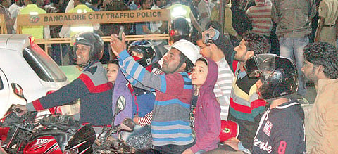 A man stops to take a selfie while on his bike near MG Road in Bengaluru on Sunday; (left) City Police Commissioner T Suneel Kumar oversees security | S Manjunath