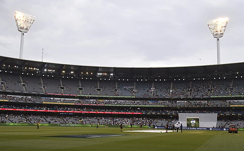 Lights are on as ground staff cover the pitch at the Melbourne Cricket Ground as rain delays the fourth day of the Ashes cricket test match between England and Australia in Melbourne, Australia, Friday, Dec. 29, 2017. | AP