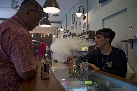 This photograph taken on January 9, 2018 shows an e-cigarette cafe employee (R) vaping beside a customer in Jakarta. (AFP)