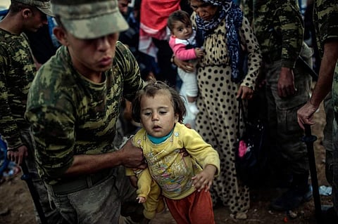 Turkish soldiers helping Kurdish families fleeing the fighting in Syria. (Photo | Associated Press)
